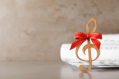 Wooden music note with red bow on table, space for text. Christmas celebration