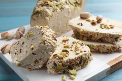 Photo of Pieces of tasty halva with pistachios on table, closeup