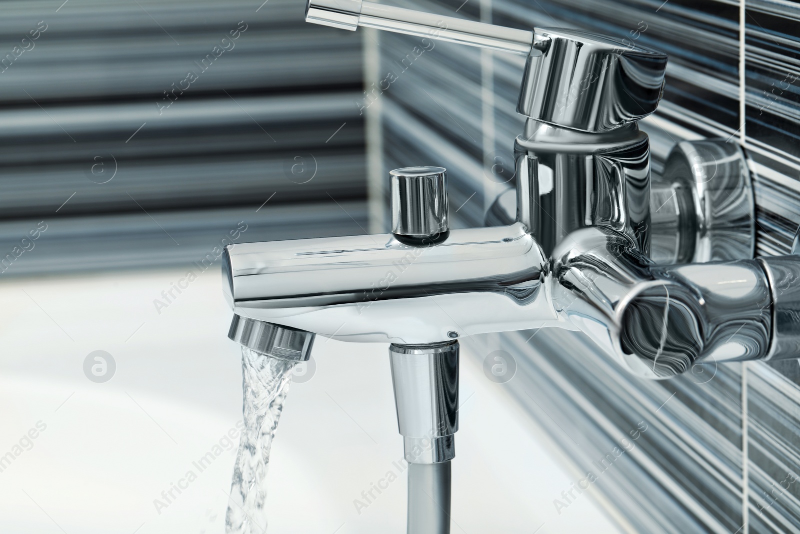 Photo of Water flowing from bath tap installed on black and white wall