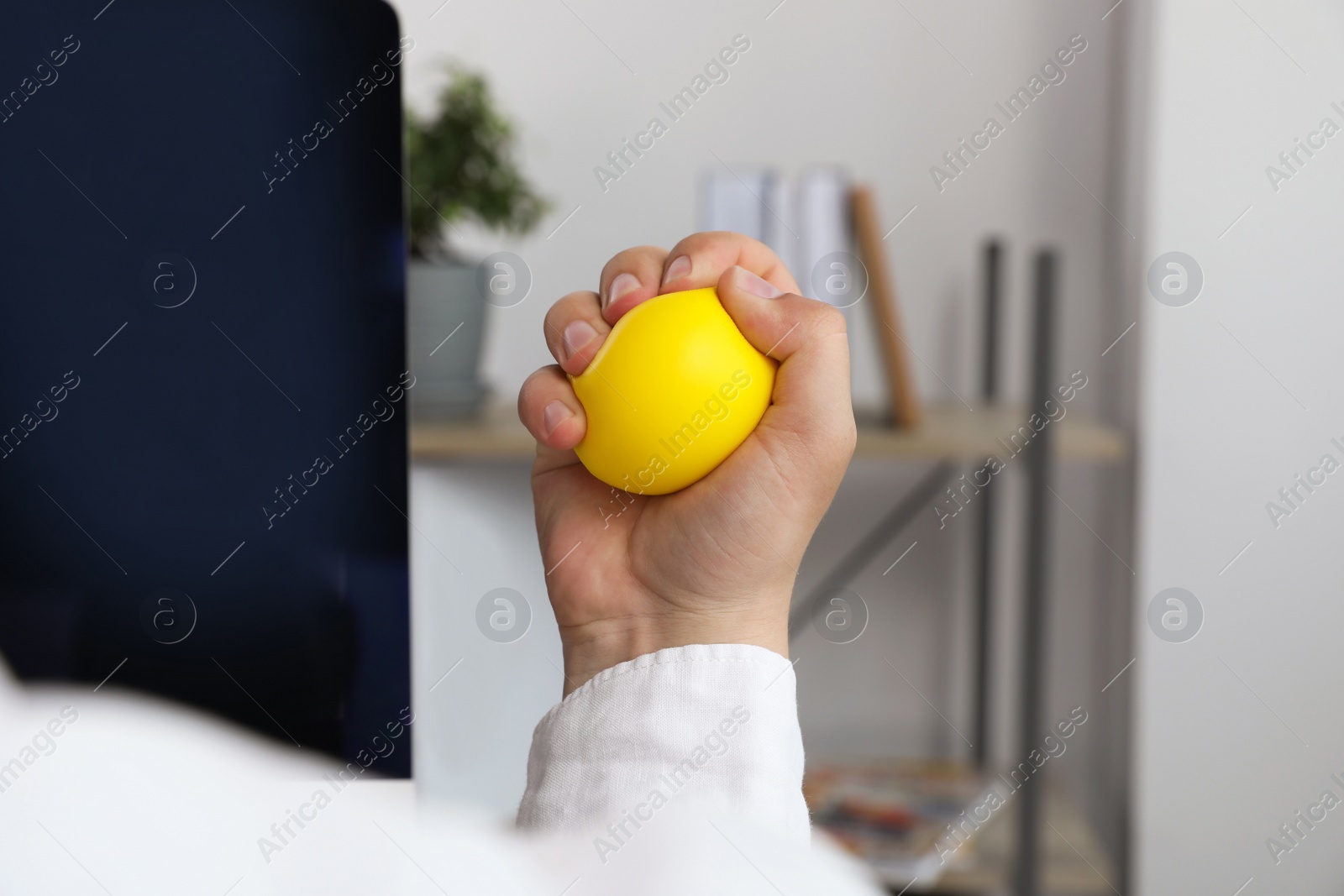 Photo of Man squeezing yellow stress ball in office, closeup