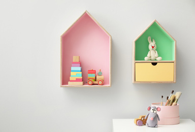 House shaped shelves and white table in children's room. Interior design