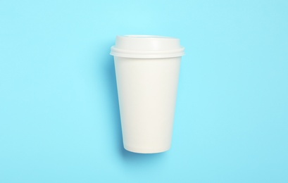 Photo of Takeaway paper coffee cup with on light blue background, top view