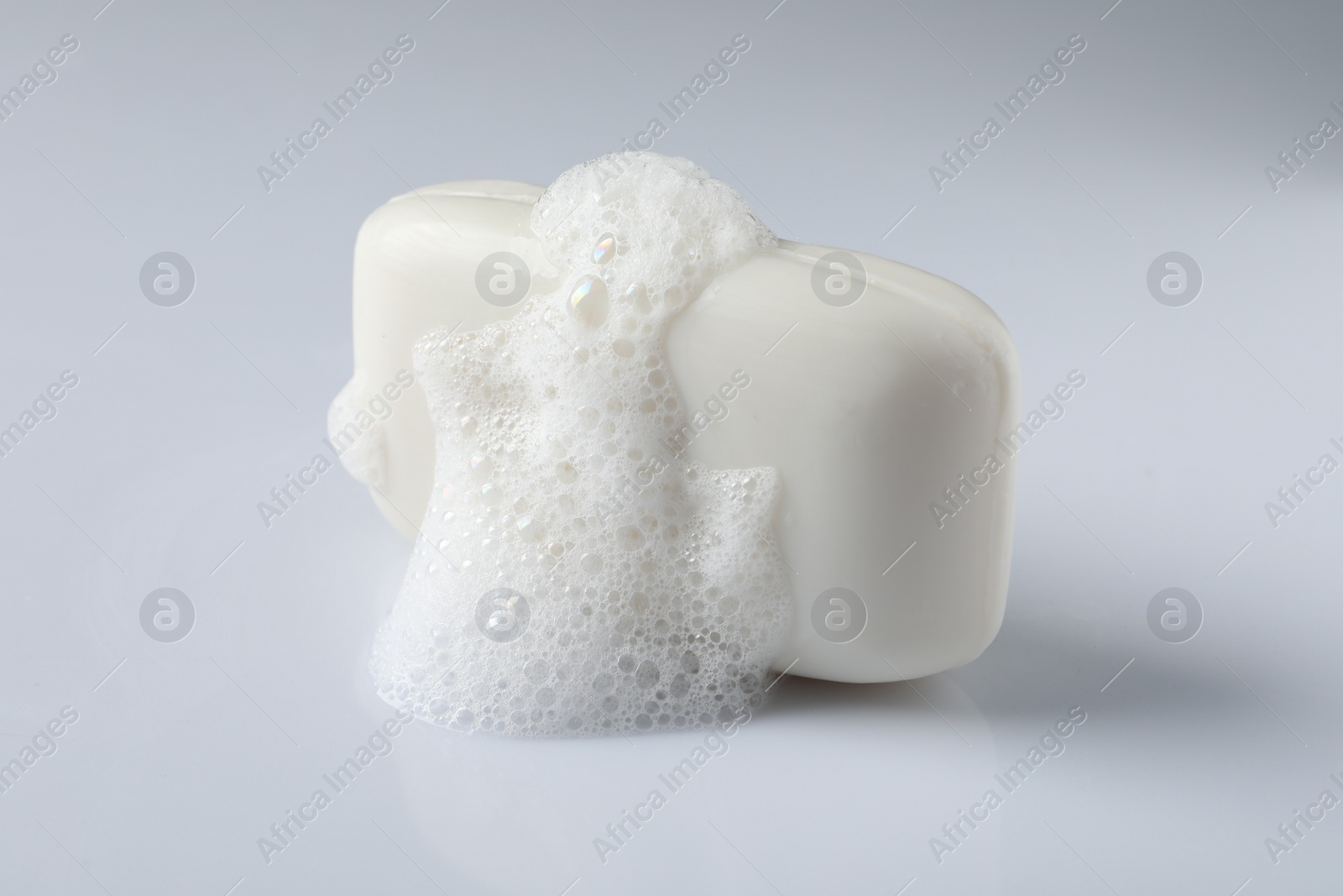 Photo of Soap with fluffy foam on white background