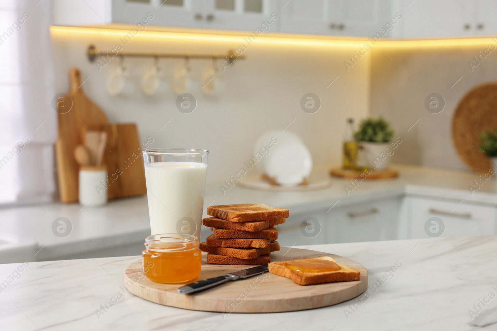 Photo of Breakfast served in kitchen. Crunchy toasts, honey and milk on white marble table