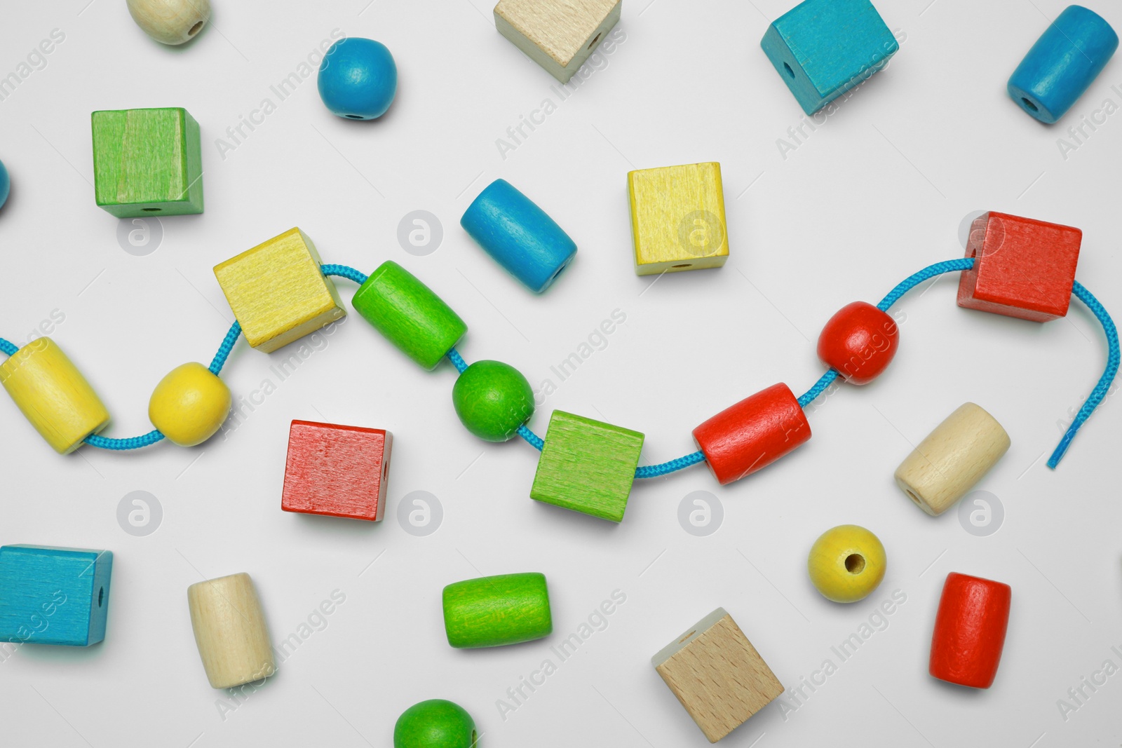 Photo of Wooden pieces and string for threading activity isolated on white, top view. Educational toy for motor skills development