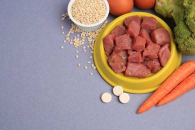 Raw meat in bowl, vitamins and products for pet on color background, flat lay. Space for text