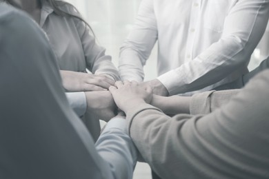 Image of Group of people holding their hands together, closeup. Black and white effect