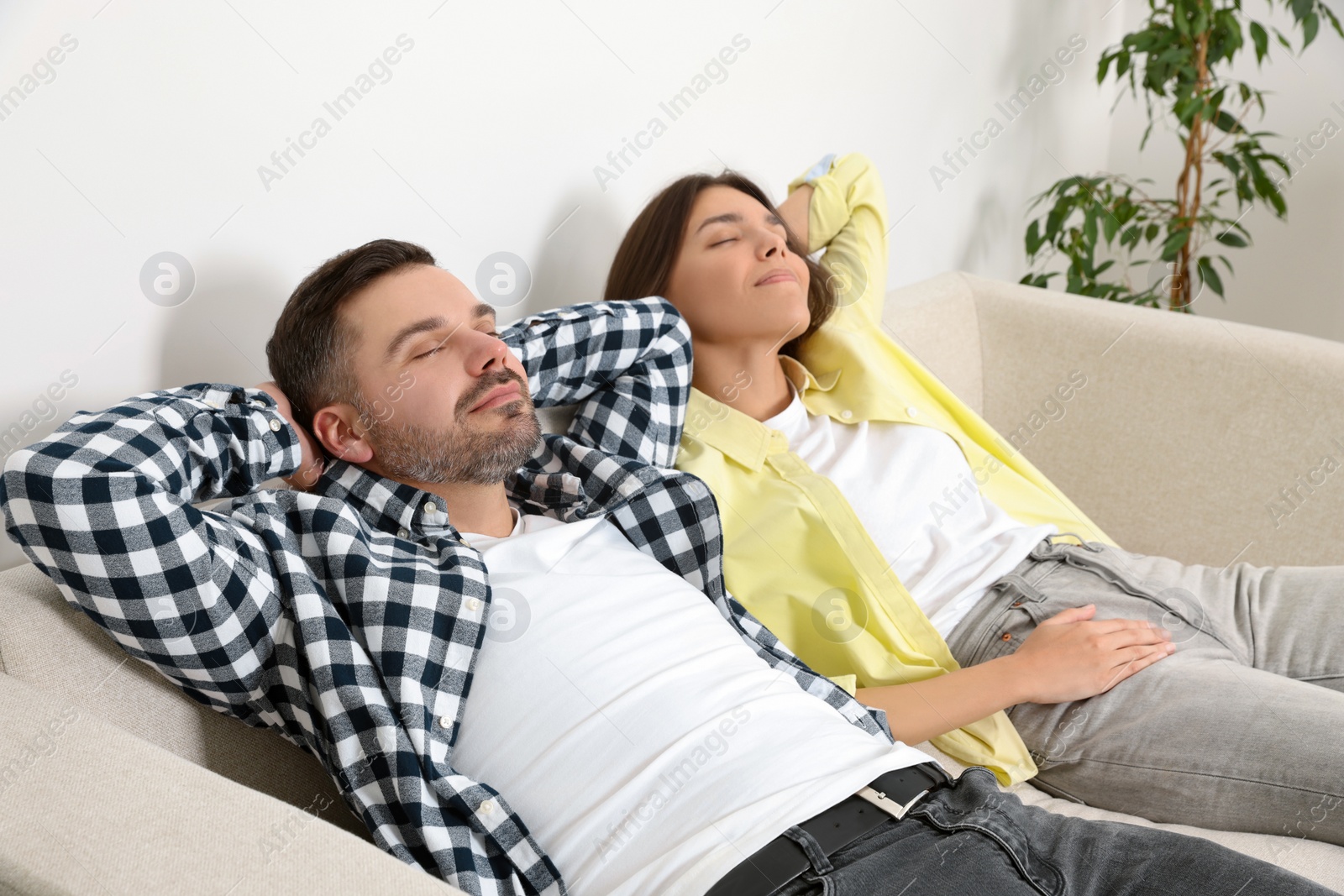 Photo of Happy couple resting on sofa in new apartment. Moving day