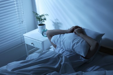 Photo of Sleepy man covering head with pillow in bed at home
