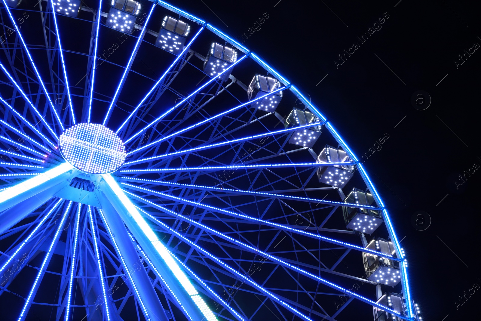 Photo of Beautiful glowing Ferris wheel against dark sky, low angle view