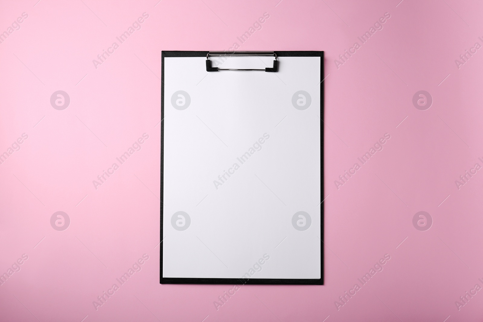 Photo of Black clipboard with sheet of blank paper on pink background, top view