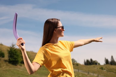 Photo of Young woman throwing boomerang outdoors on sunny day