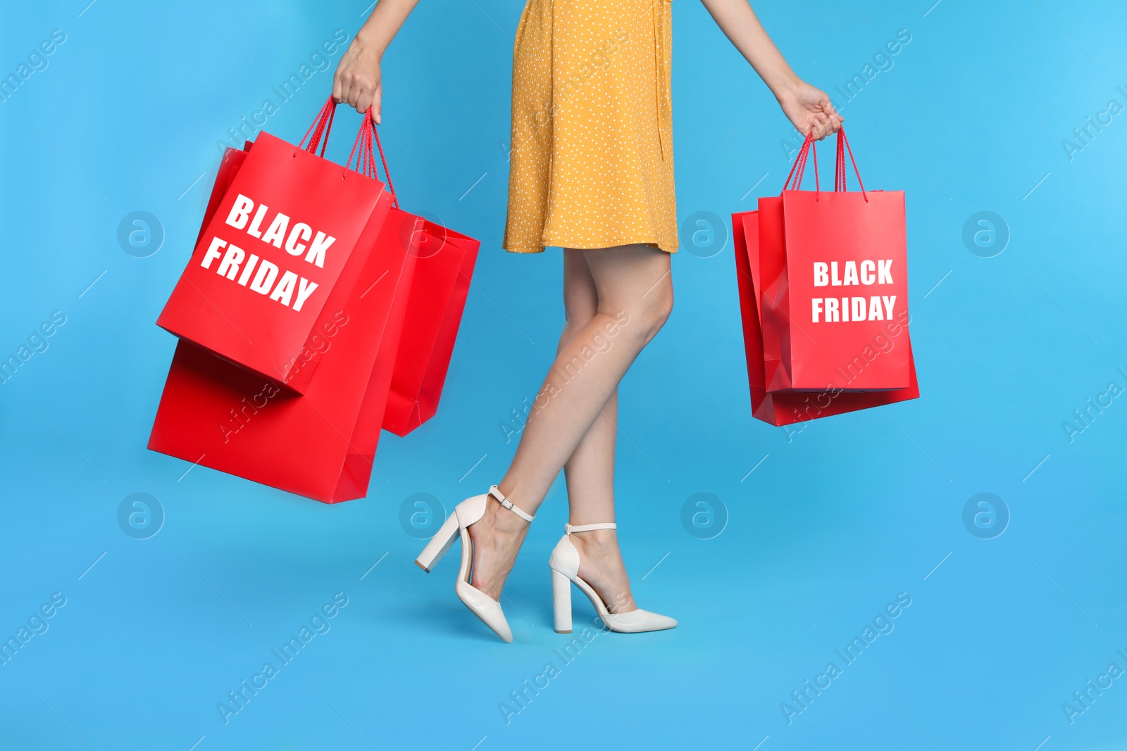 Photo of Woman with shopping bags on light blue background, closeup. Black Friday