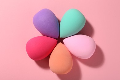 Photo of Many different makeup sponges on pink background, top view