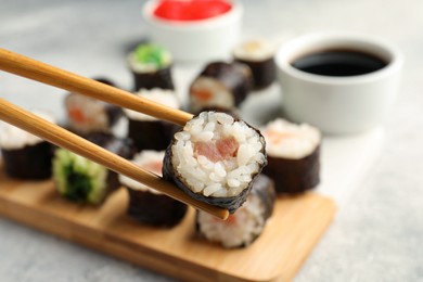 Photo of Set of delicious sushi rolls and chopsticks, closeup