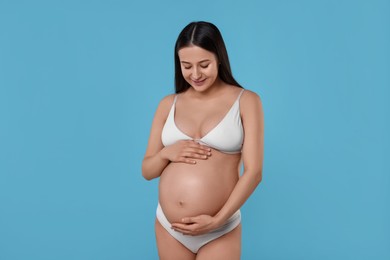 Photo of Beautiful pregnant woman in stylish comfortable underwear on light blue background