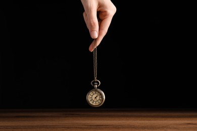 Psychotherapist with pendulum on black background, closeup. Hypnotherapy session