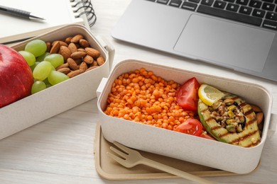 Photo of Healthy products high in vegetable fats near laptop on light wooden table, closeup