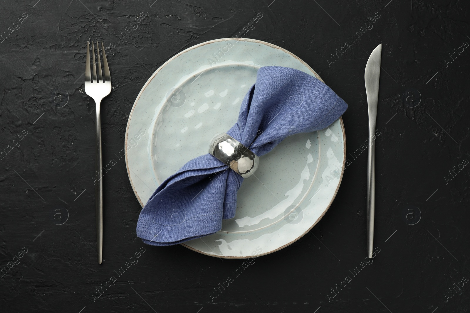 Photo of Stylish setting with cutlery, napkin and plate on dark textured table, flat lay