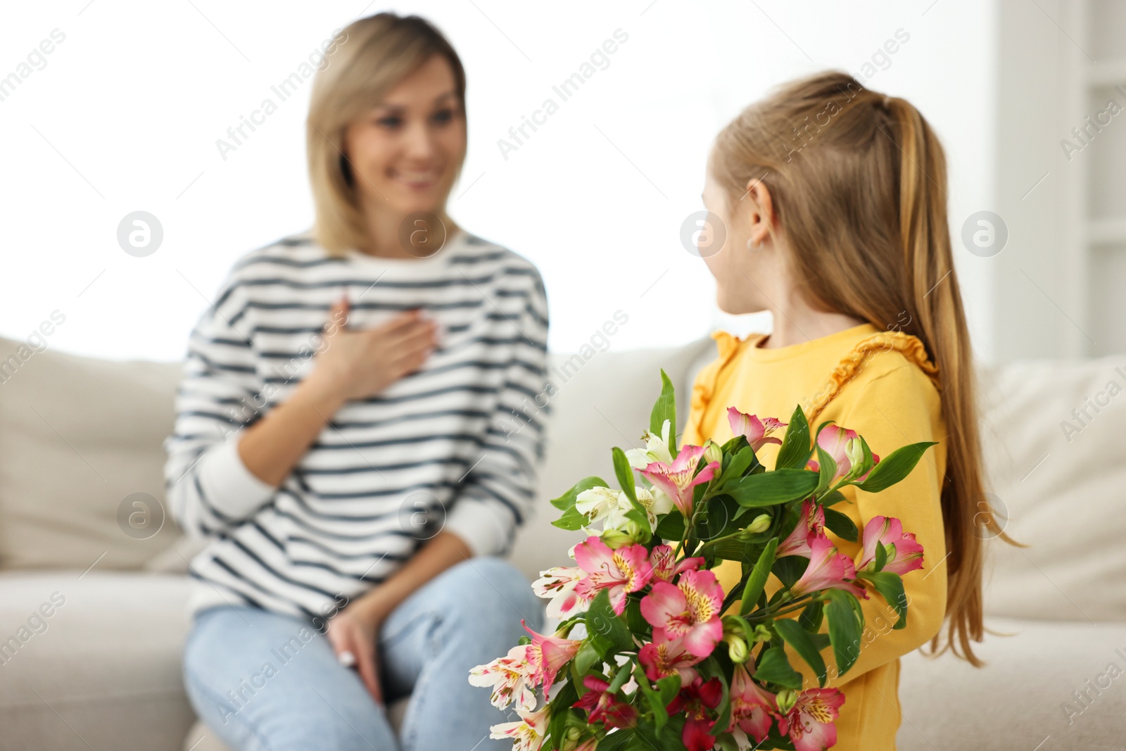 Photo of Little girl hiding bouquet of alstroemeria flowers for mom at home, selective focus. Happy Mother's Day