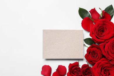 Photo of Blank card, beautiful red roses and petals on white background, flat lay. Space for text