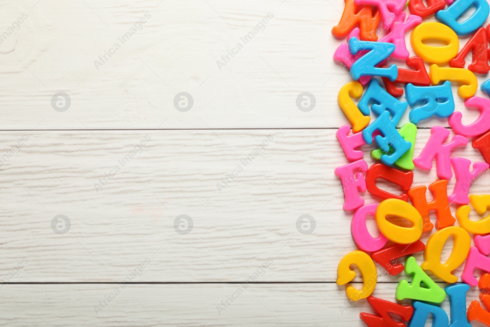 Photo of Colorful magnetic letters on white wooden table, flat lay. Space for text