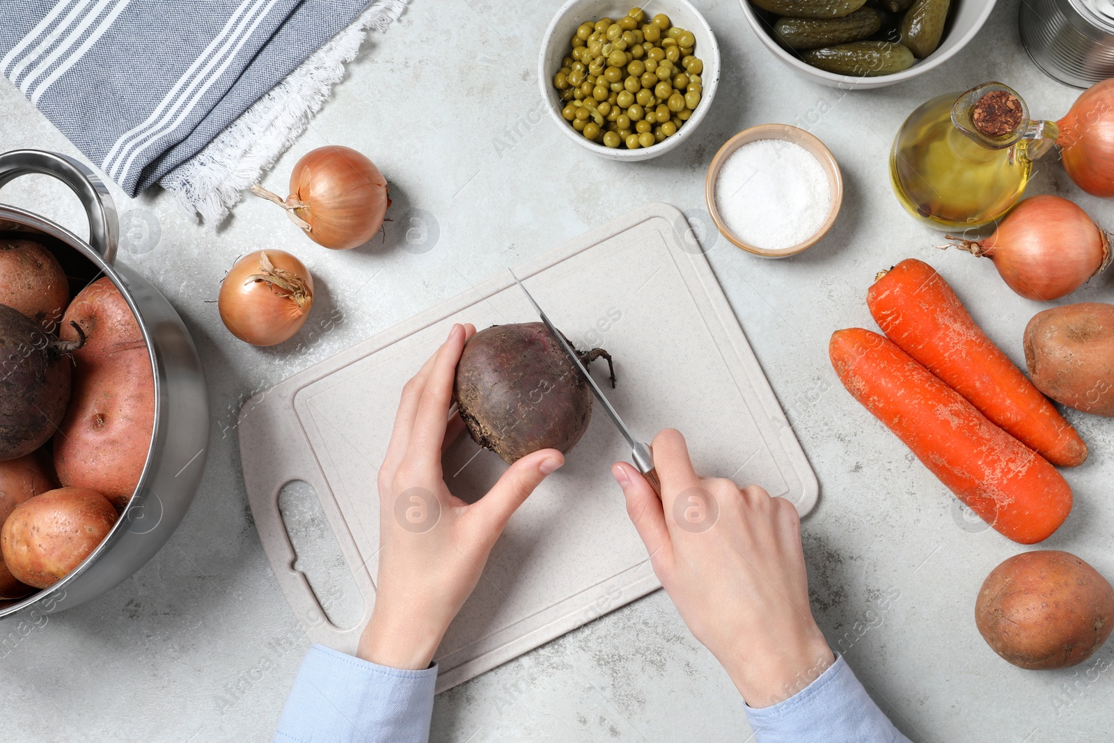 Photo of Woman peeling beetroot at white table, top view. Cooking vinaigrette salad