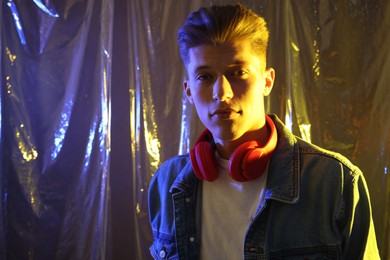 Photo of Young man with headphones in neon lights. Space for text