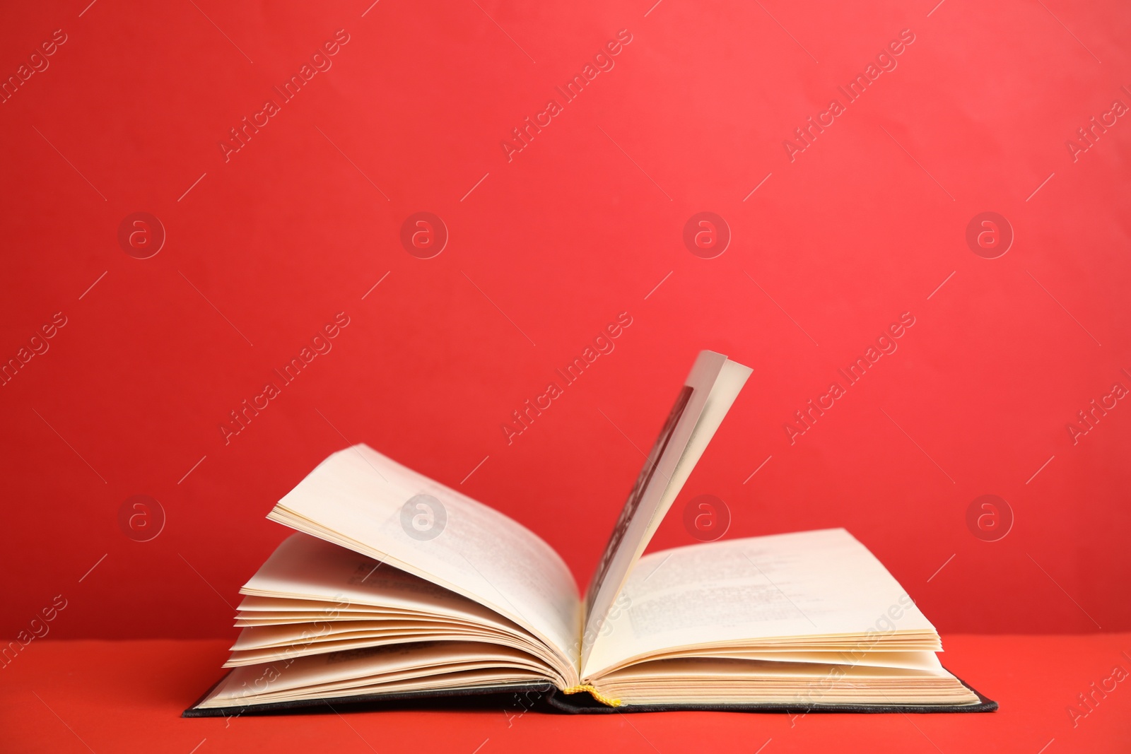 Photo of Open old hardcover book on red background. Space for text