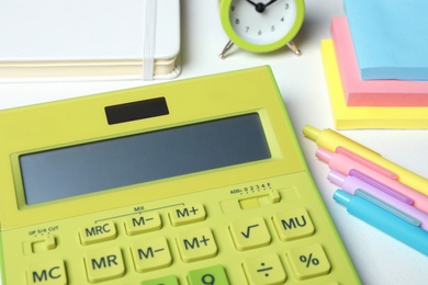 Photo of Calculator, alarm clock and stationery on white table, closeup. Tax accounting