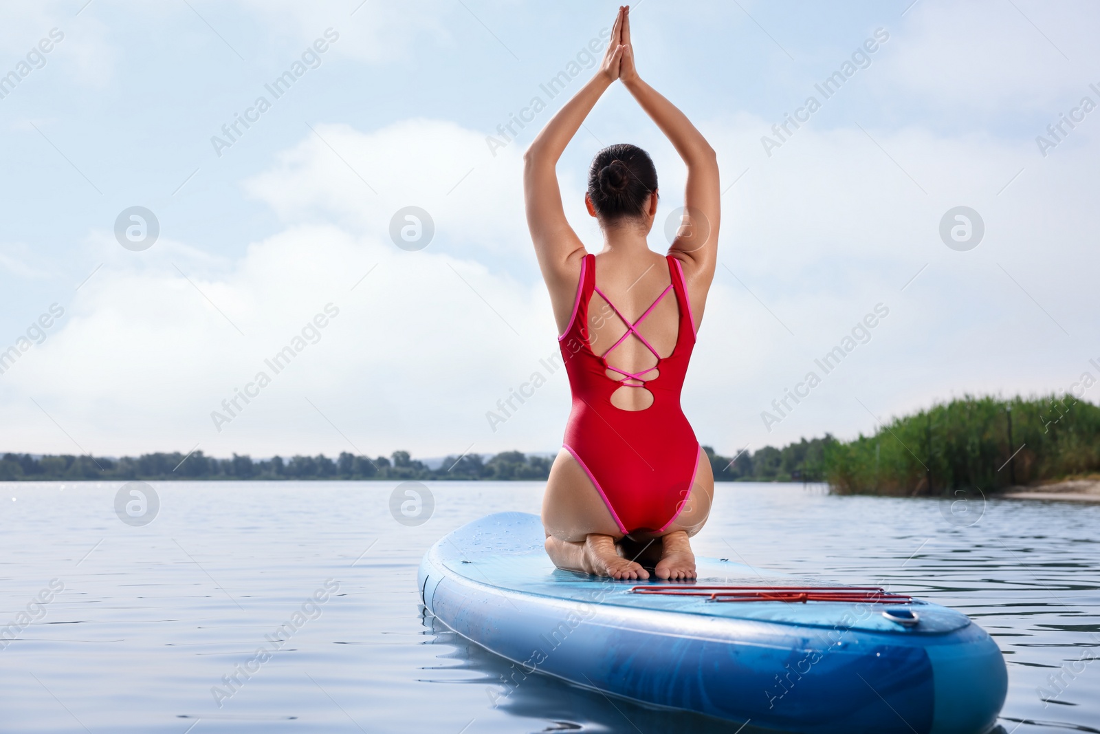 Photo of Woman practicing yoga on light blue SUP board on river, back view. Space for text