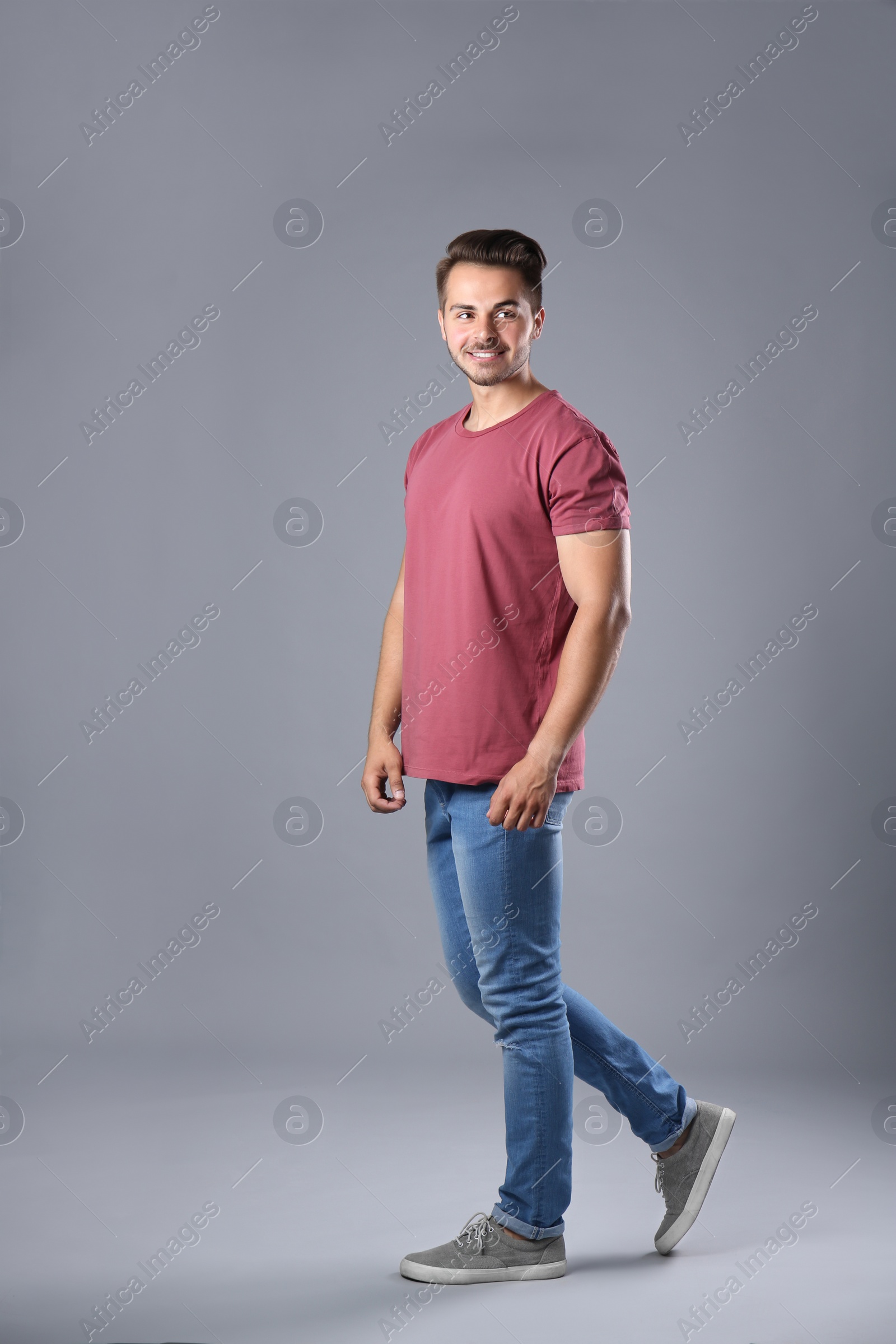 Photo of Young man in stylish jeans on grey background