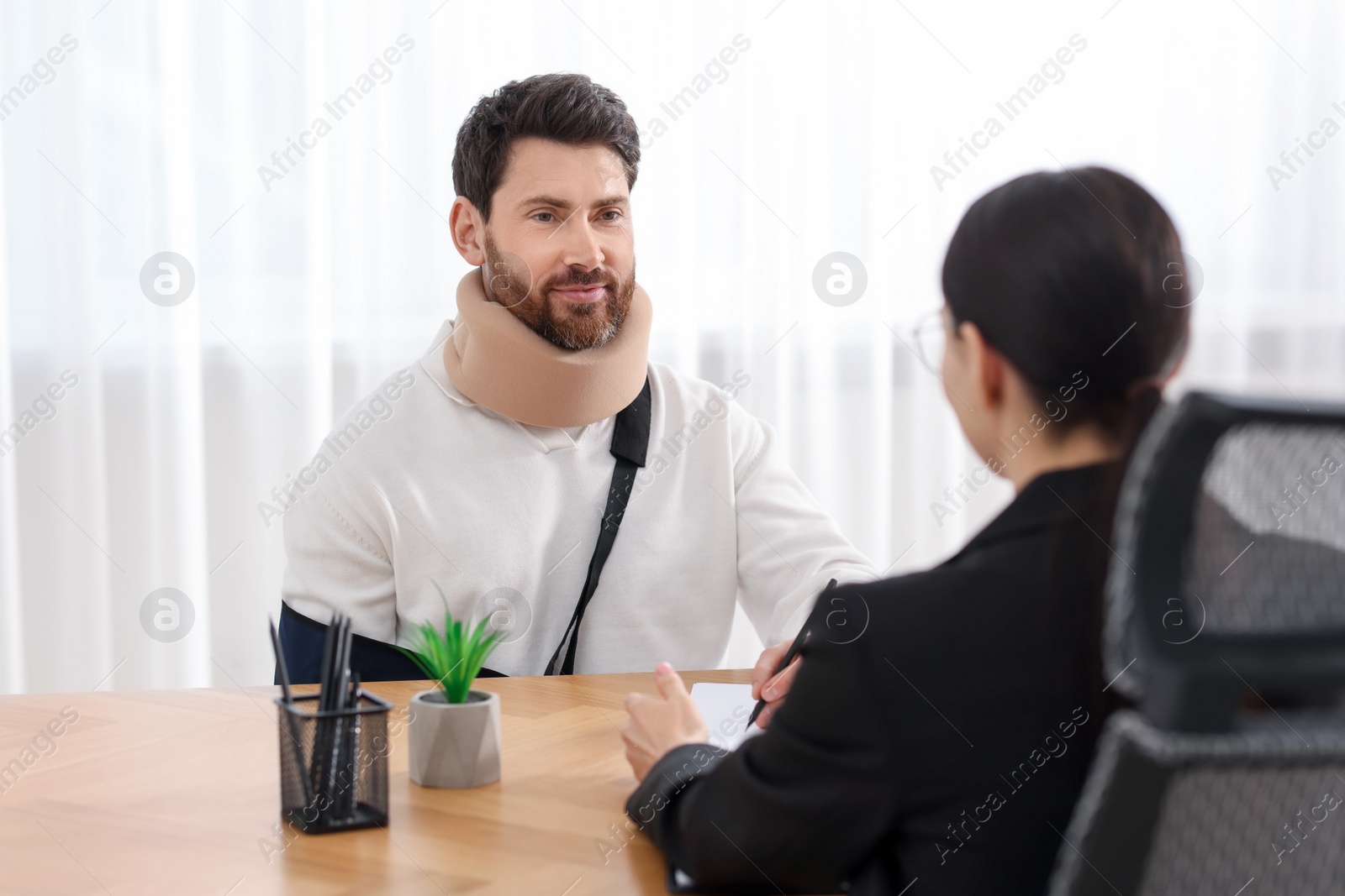 Photo of Injured man having meeting with lawyer in office, selective focus