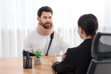 Photo of Injured man having meeting with lawyer in office, selective focus