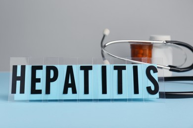 Photo of Word Hepatitis and medical supplies on light blue table