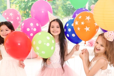 Cute girls with balloons at birthday party indoors