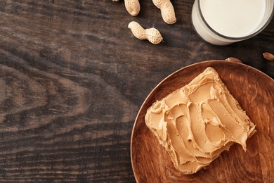 Photo of Tasty toast with peanut butter on wooden plate