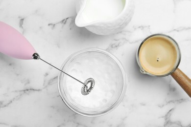 Photo of Flat lay composition with mini mixer (milk frother), whipped milk in glass and coffee at white marble table