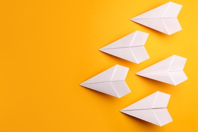 Photo of Handmade white paper planes on yellow background, flat lay. Space for text