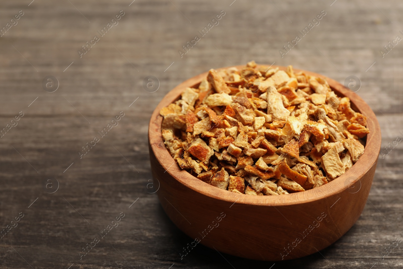 Photo of Bowl of dried orange zest seasoning on wooden table. Space for text