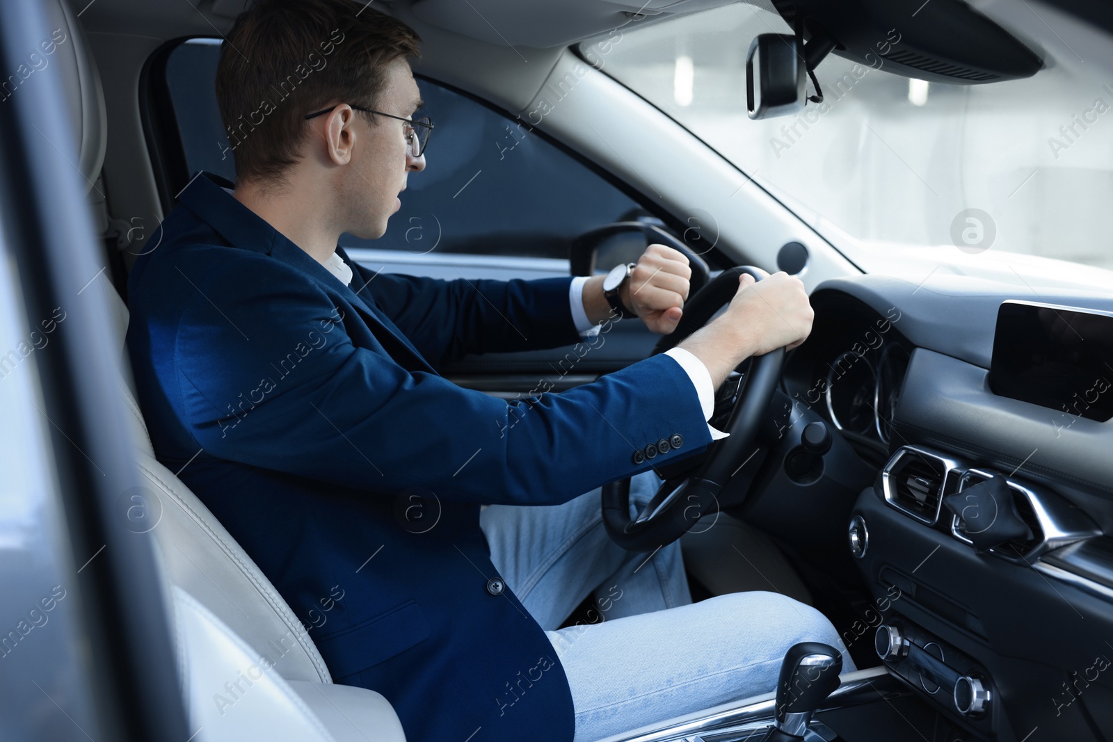 Photo of Young man checking time in car. Being late