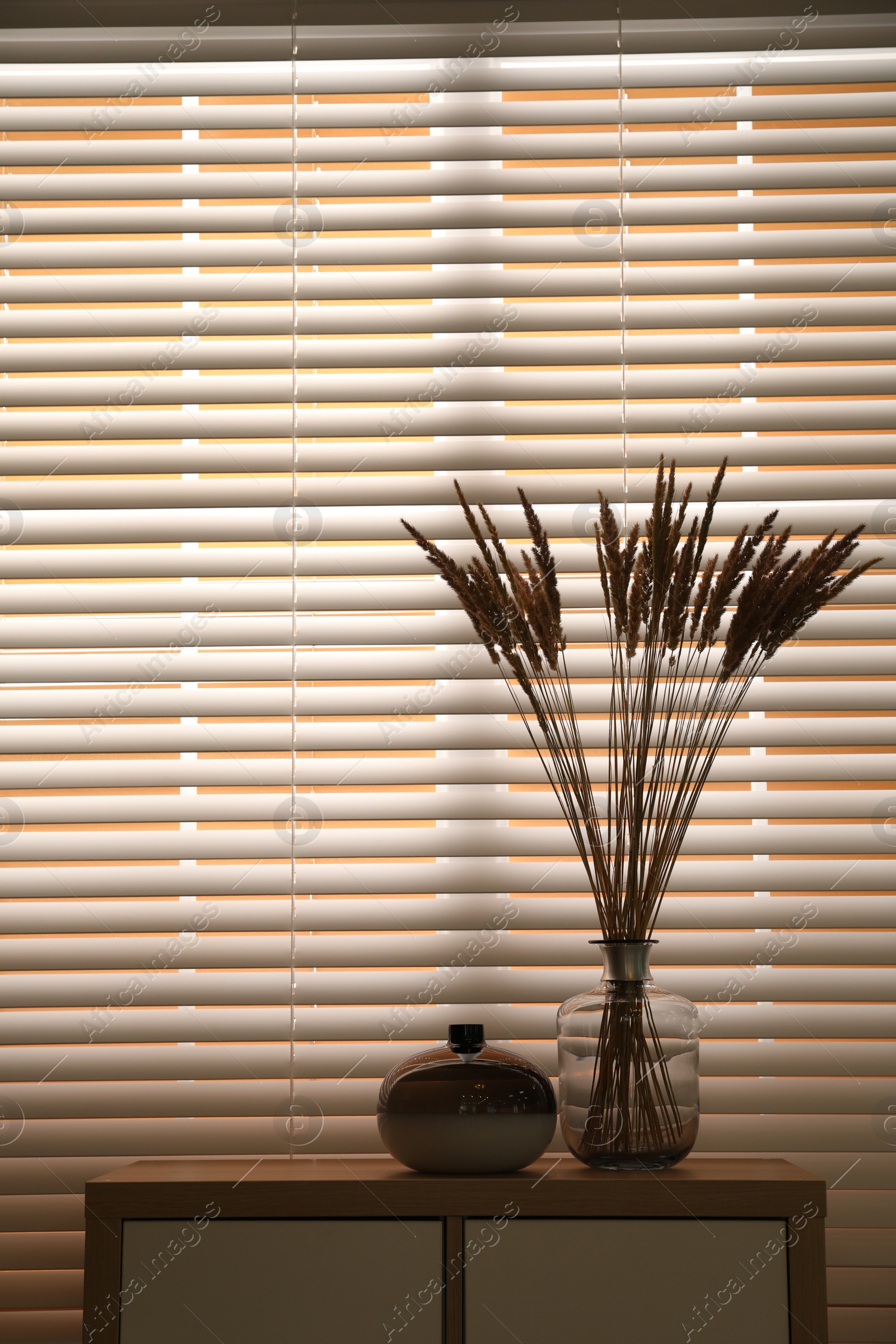 Photo of Decorative vases on commode near window indoors