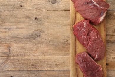 Pieces of raw beef meat on wooden table, top view. Space for text