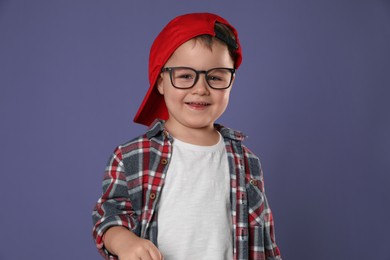Photo of Cute little boy in glasses on purple background