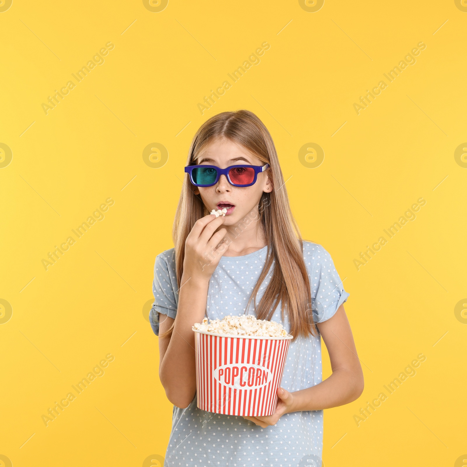 Photo of Emotional teenage girl with 3D glasses and popcorn during cinema show on color background