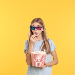 Photo of Emotional teenage girl with 3D glasses and popcorn during cinema show on color background