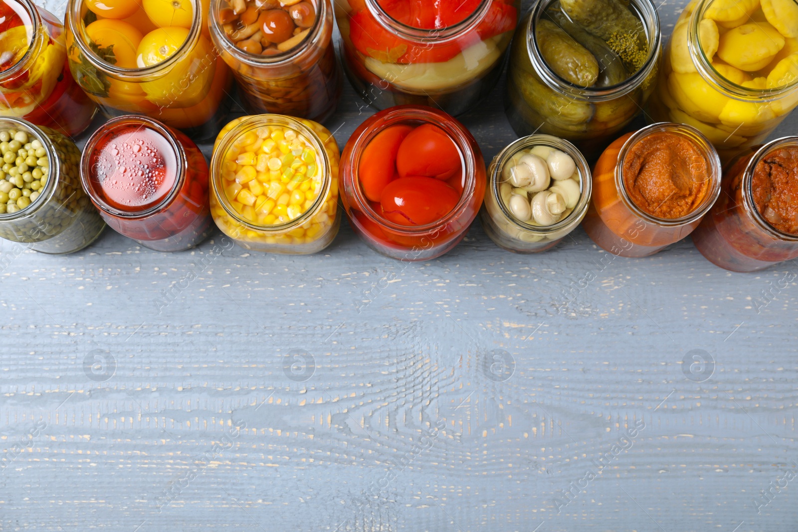 Photo of Jars of pickled vegetables on light wooden table, flat lay. Space for text