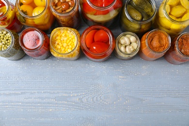 Photo of Jars of pickled vegetables on light wooden table, flat lay. Space for text