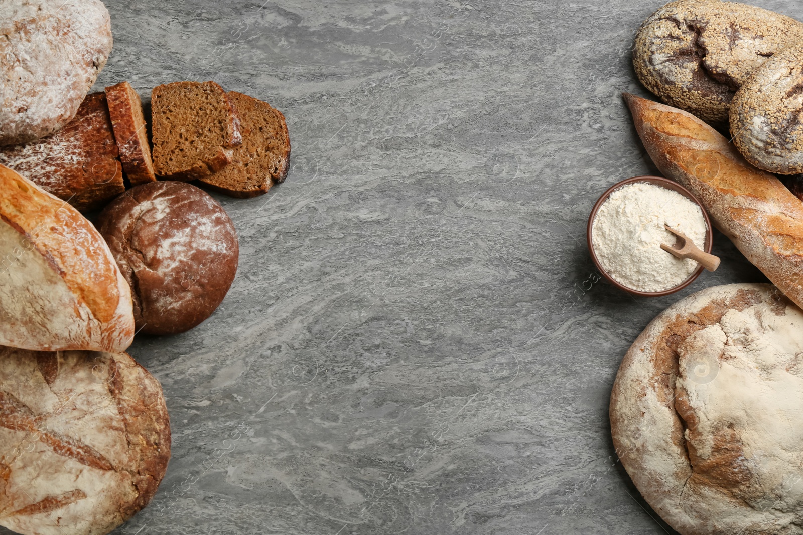 Photo of Different kinds of fresh bread on grey table, flat lay. Space for text