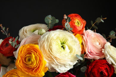 Photo of Bouquet with beautiful bright ranunculus flowers on dark background, closeup